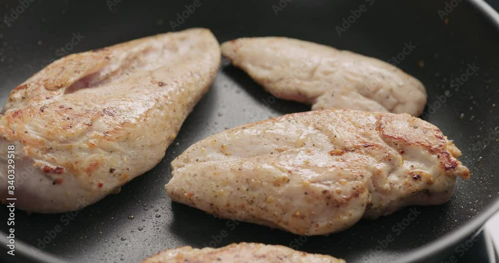 Slow motion handheld shot of chicken fillet frying on non-stick pan Slow motion handheld shot of chicken fillet frying on non-stick pan