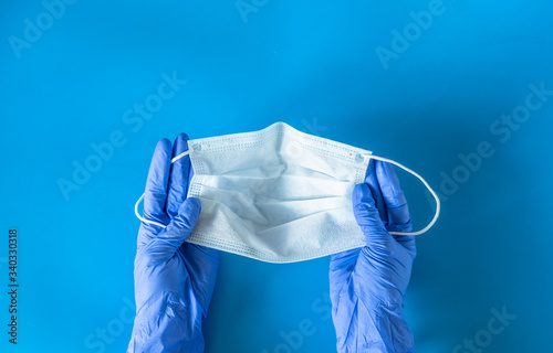 Hands in medical gloves hold a protective face mask. Concept of protection against bacteria and coronavirus.