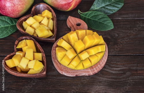 diced mangoes in two wooden bowls and whole mangoes on the table close-up. background with mango. fresh mango close-up.