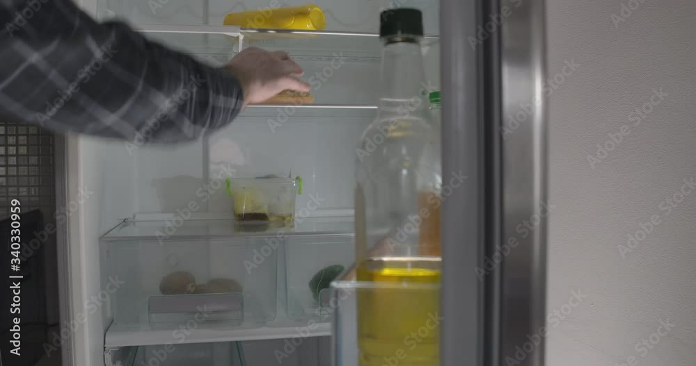 Male Caucasian hand opening grey fridge, taking bun and leaving. Unrecognizable adult man having meal indoors. Cinema 4k ProRes HQ. Male Caucasian hand opening grey fridge, taking bun and leaving. Unrecognizable adult man having meal indoors. Cinema 4k ProRes HQ.