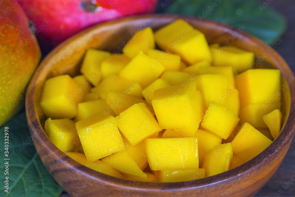 sliced mangoes in a wooden bowl macro. background with sliced fresh mangoes. background with mango slices in a bowl close-up.