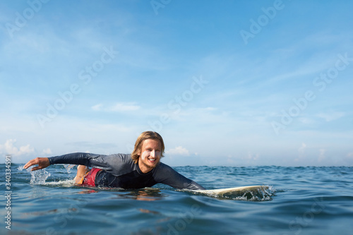 Surfing. Handsome Surfer In Wetsuit On Surfboard. Portrait of Man Swimming In Ocean. Waved Water Surface,  Water Sport Livestyle  © puhhha