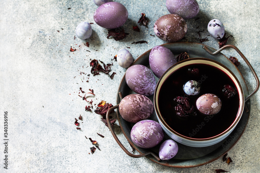 Natural egg dye purple. Easter eggs are painted with natural egg dye from Hibiscus tea on a gray stone countertop. Copy space. Natural egg dye purple. Easter eggs are painted with natural egg dye from Hibiscus tea on a gray stone countertop. Copy space.