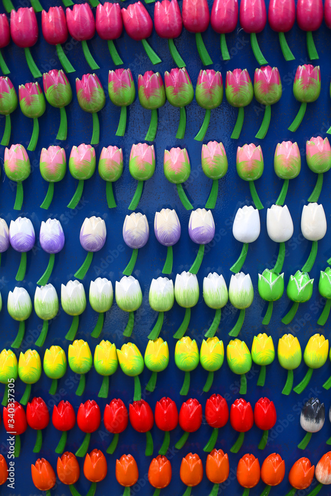 Fototapeta premium Colorful miniature tulips, wooden flower magnets. Typical Dutch souvenirs for tourists in a shop from Amsterdam, Netherlands. Typical Amsterdam symbol. Selective focus. 