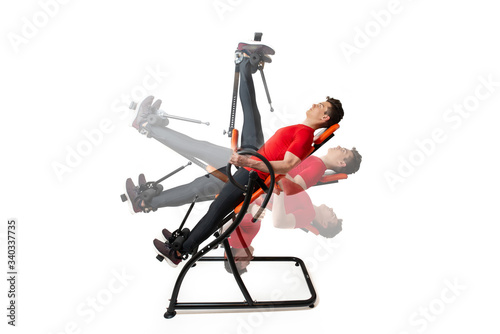 Man doing exercise on inversion table for his back pain, isolated on white. Multiple positions.