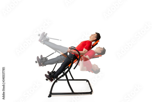 Man doing exercise on inversion table for his back pain, isolated on white. Multiple positions.