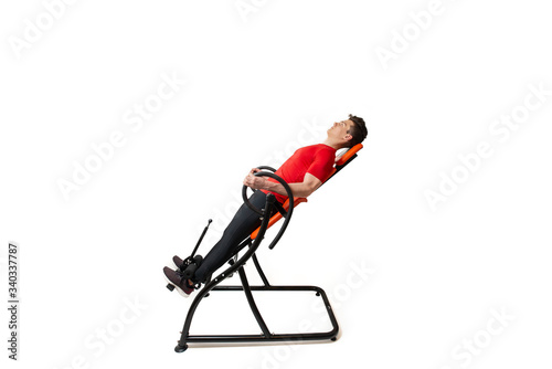 Fotografia Man doing exercise on inversion table for his back pain, isolated on white