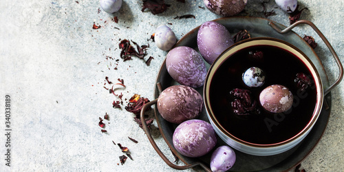Natural egg dye purple. Easter eggs are painted with natural egg dye from Hibiscus tea on a gray stone countertop. Banner.