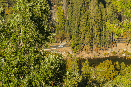 Car drives along El Portal Road by the Merced River in Yosemite National Park, California, USA.