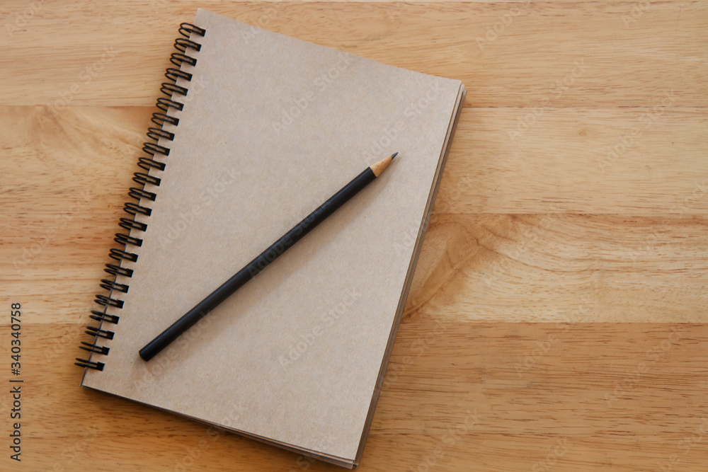 Brown notebook and pencil on wooden table; education concept Brown notebook and pencil on wooden table; education concept