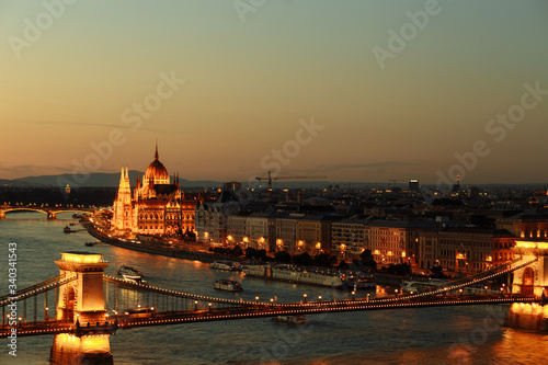 night view of the city of Budapest on the Danube river on which ships with illuminated bridge and parliament sail