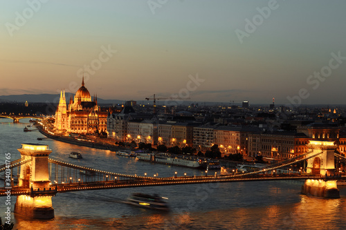 night view of the city of Budapest on the Danube river on which ships with illuminated bridge and parliament sail © Taras