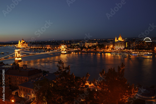 night view of the city of Budapest on the Danube river on which ships with illuminated bridge and parliament sail