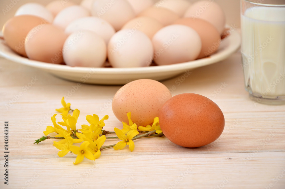eggs on a wooden background and twigs and a glass of milk and a plate with eggs in the background eggs on a wooden background and twigs and a glass of milk and a plate with eggs in the background