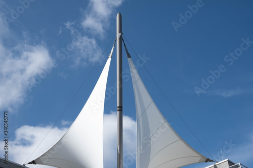 white sails with a mast over a building on a blue sky