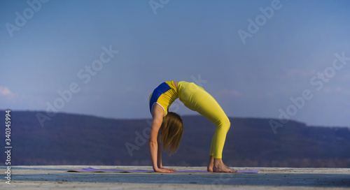 Young gymnast girl perform various gymnastic and yoga exercises, including splits and bending over backwards in front of the camera. photo