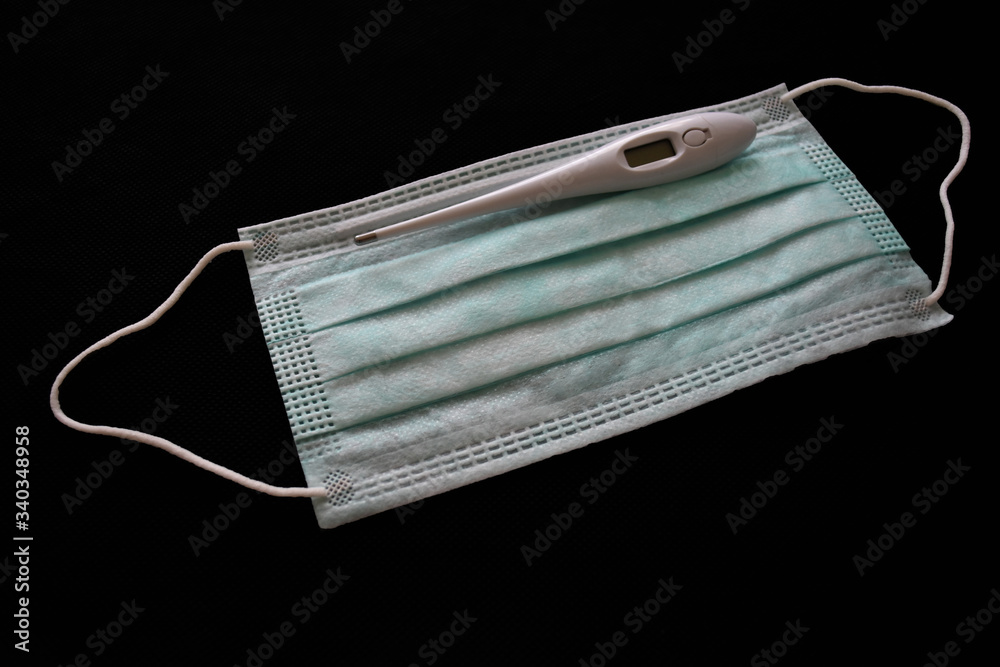 Thermometer and protective face mask while having cold, flu, Corona virus, Covid - 19 Thermometer and protective face mask while having cold, flu, Corona virus, Covid - 19