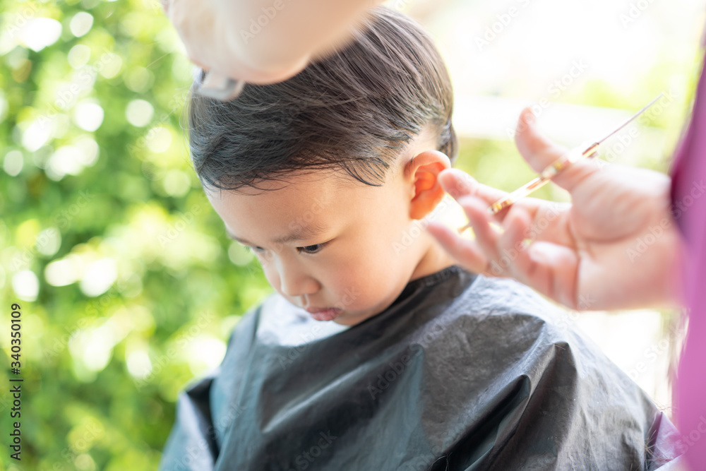 Grandma was cutting hair for her nephew at home in the garden. Grandma was cutting hair for her nephew at home in the garden.