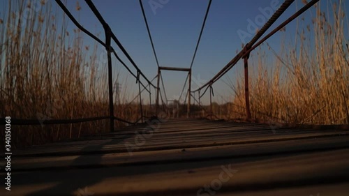 Petrovo, Dnipro / Ukraine - April 15 2020
Old suspension bridge over the river. Wooden bridge on steel cables. Village bridge. photo