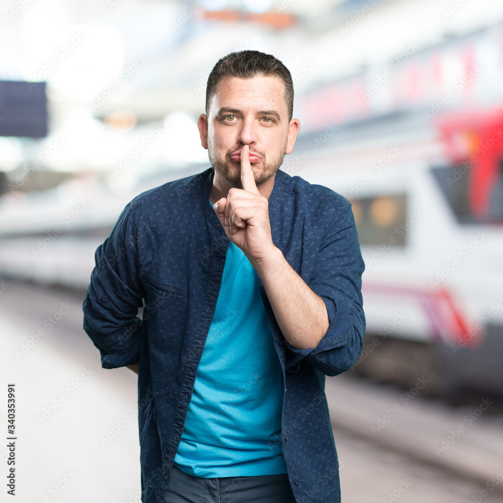 Young man wearing a blue outfit. Doing silence gesture. Young man wearing a blue outfit. Doing silence gesture.