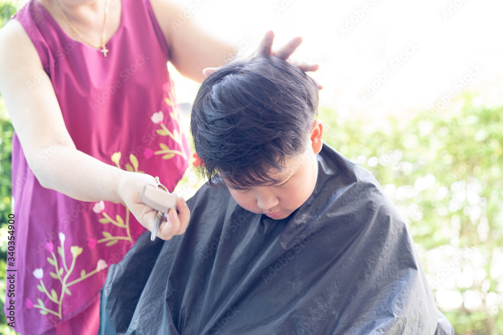 Obraz premium Grandma was cutting hair for her nephew at home in the garden.