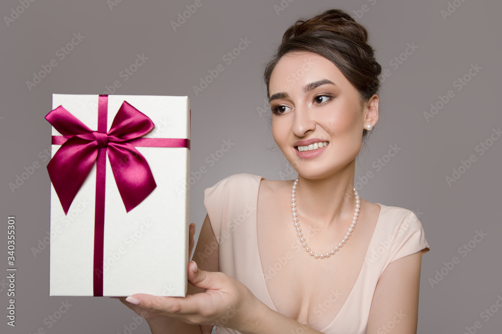happy woman with a gift. Pink dress. grey background happy woman with a gift. Pink dress. grey background
