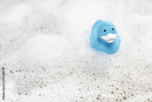 Fotografie Blue rubber duck swimming in the bathtub with foam