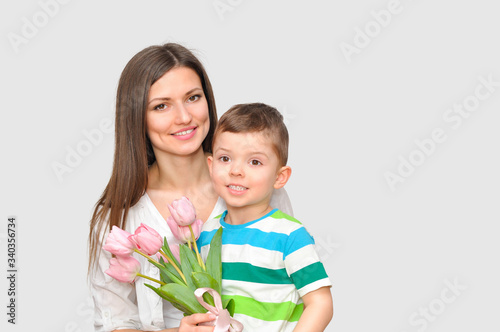 Little child son gives his mother a bouquet of delicate pink tulips. Mother's Day celebration.	