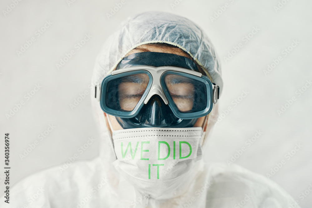Doctor after a long battle with the virus in bio suit and protective mask with the inscription We did it. Doctor after a long battle with the virus in bio suit and protective mask with the inscription We did it.