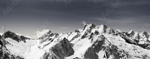 Panorama of snow-capped mountain peaks and sky with clouds photo