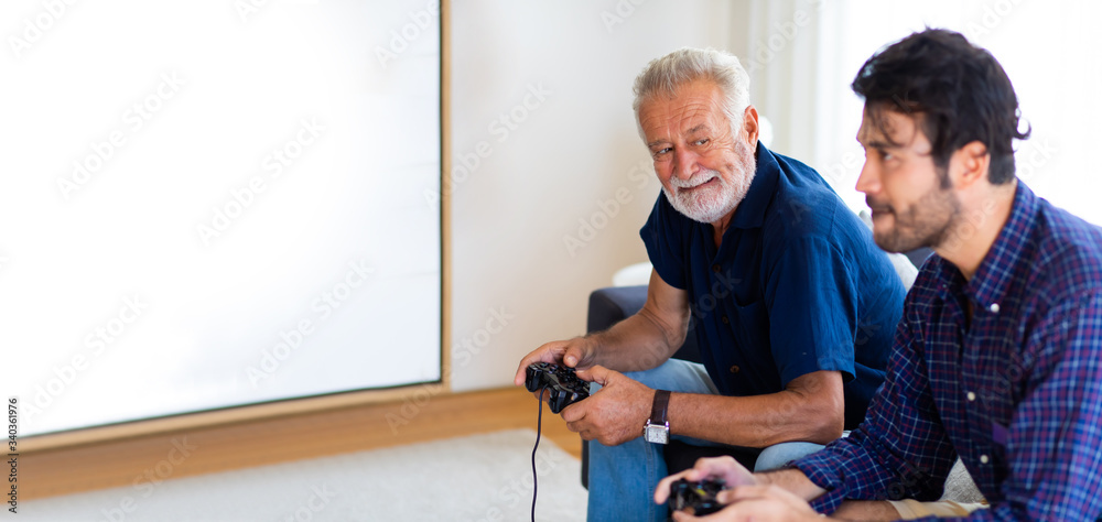 Father and son family time together at home concept. Happy father and son enjoy playing video games with joysticks in living room at home Father and son family time together at home concept. Happy father and son enjoy playing video games with joysticks in living room at home