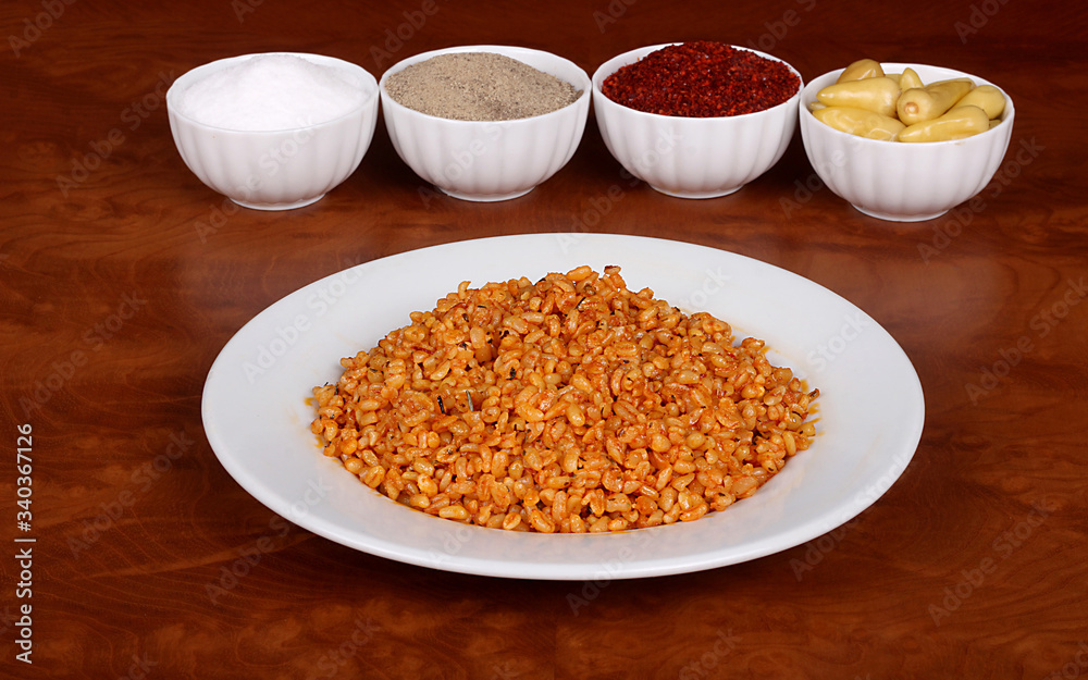 Cooked oatmeal with delicious tomato sauce ready to serve on a white plate with special Turkish spices on a wooden table Cooked oatmeal with delicious tomato sauce ready to serve on a white plate with special Turkish spices on a wooden table
