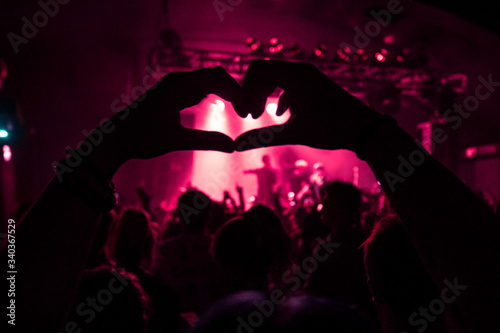 a crowd member holding the love sign up at a concert