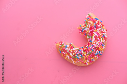 Half eaten donut on pink background 