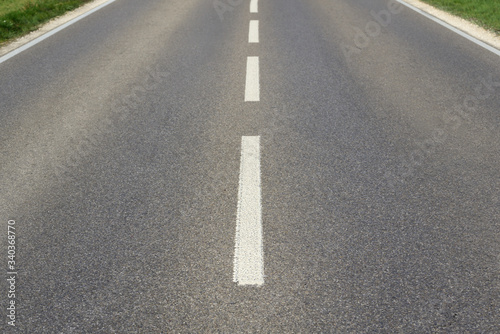 Background with a wide empty paved road and median that stretches from one edge of the picture to the other