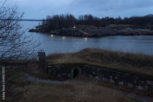 Fototapeta Naklejka Na Ścianę i Meble -  Evening lights of a rocky island and a view of the old fortified old fortified island of Fort Suomenlinna, Sveaborg near Helsinki in Finland in autumn twilight.