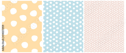 3 Varius Dots Seamless Vector Patterns. Irregular Hand Drawn Simple Dotted Print. Pastel Color Nursery Backdrop. Infantile Style Design. White Freehand Dots on a Blue, Pink and Yellow Layout. 