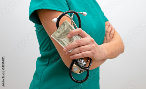 Corrupt female doctor. Nurse with money and stethoscope. The costs of medical services concept. photo