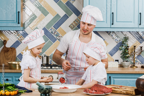 Happy family in the kitchen. Father and children prepare food together in the kitchen at home. The concept of cooking.