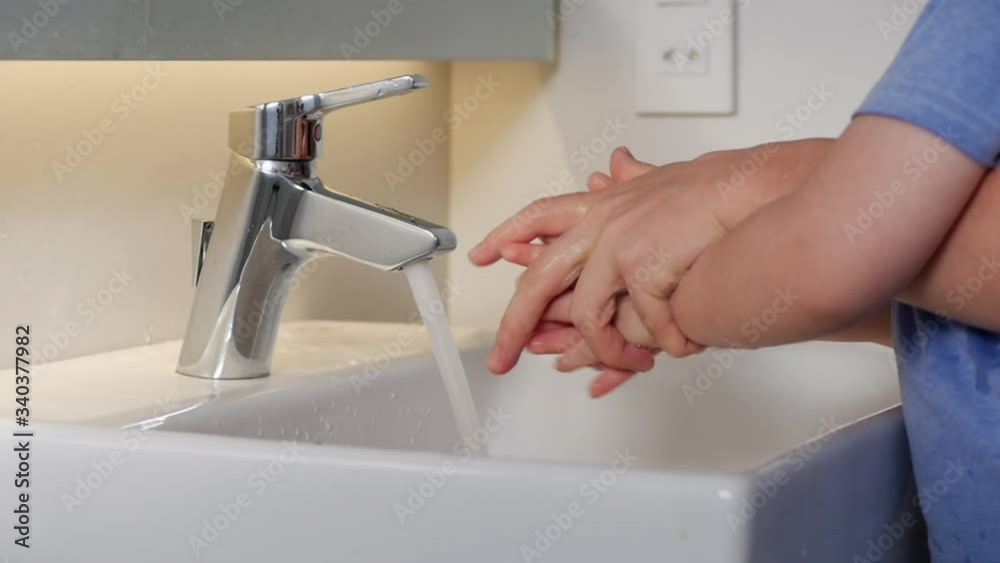 Parent mom is washing her son’s hands with soap and water to prevent