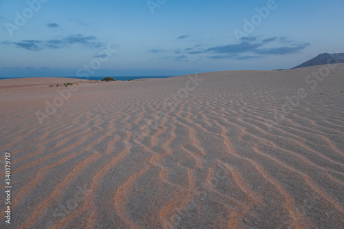 Ripples on sand dune near Corralejo with volcano mountains in the background, Fuerteventura, Canary Islands, Spain. October 2019