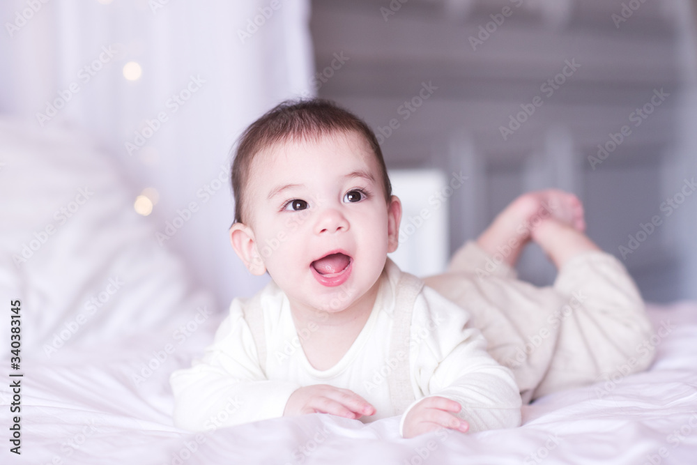 Laughing baby boy under 1 year old lying in bed closeup. Good morning. Childhood.