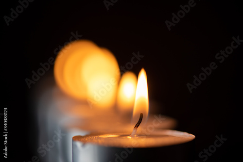 Several candles burning in a row. Photographed close-up.