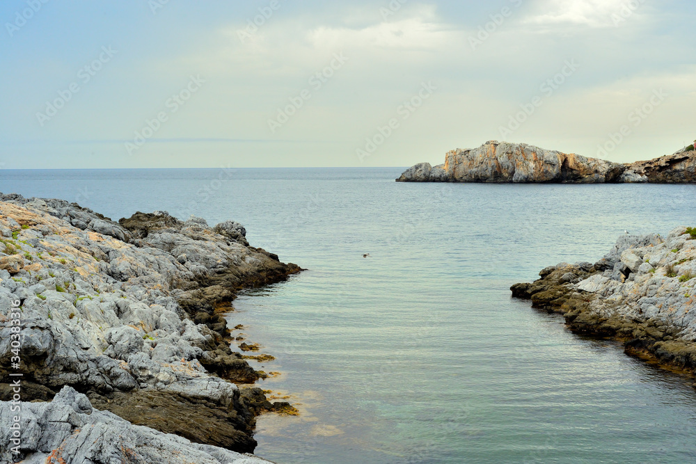 paisaje marítimo con rocas y algas marinas y cielo con nubes en la costa mediterránea de España