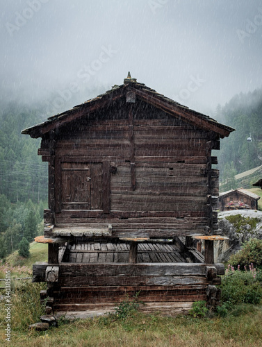 Rain drops falling on a traditional swiss mountain hut near Zermatt. The structure is supported by the typical staddle stones photo
