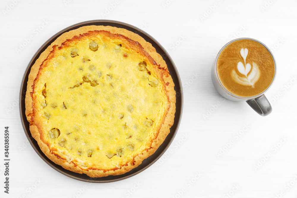 Homemade gooseberry pie with yogurt filling and cup of coffee cappuccino on white wooden table. Top view. Homemade gooseberry pie with yogurt filling and cup of coffee cappuccino on white wooden table. Top view.