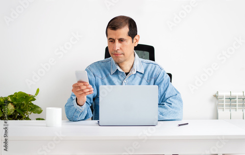 Cropped shot of a young businessman standing alone in his home office and texting on his cellphone