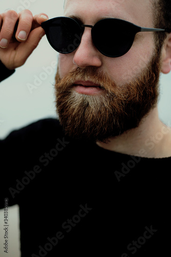 young man with beard and glasses on beach near sea