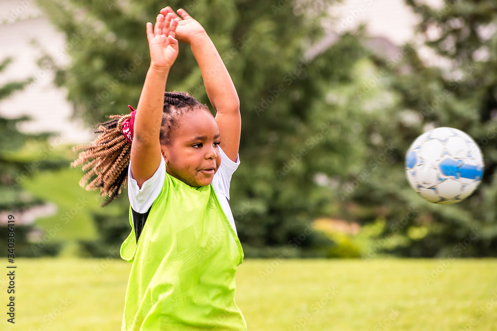 Obraz premium A young African American girl is learning how to play soccer on a sunny day 