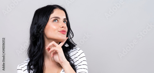 Young woman in a thoughtful pose on a gray background
